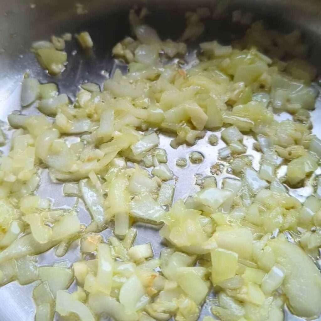onions and garlic in a pan sautéing in chorizo fat to make pasta sauce.