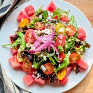 goat cheese watermelon salad with pickled onions and cherry tomatoes.