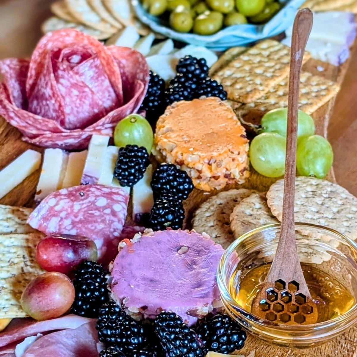 blackberry charcuterie board with cheese berries and meats like salami and prosciutto