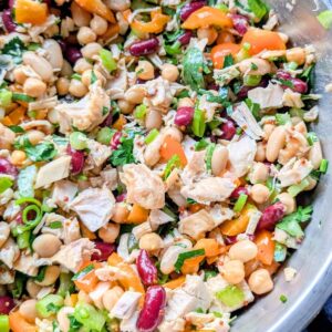 a bowl of dense bean salad with chicken and kidney beans, chickpeas, and cannellini beans and veggies