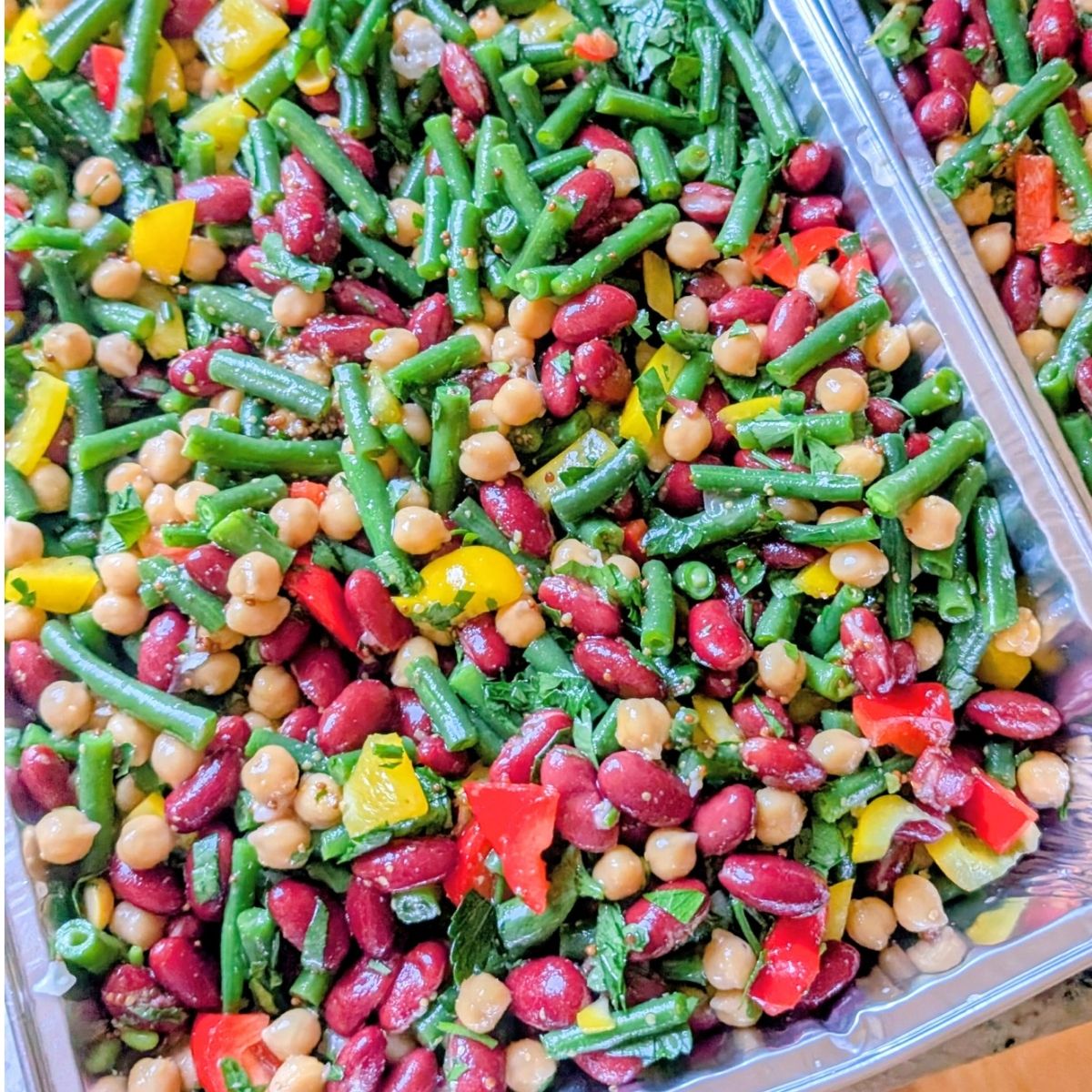 a pan of fresh bean salad with green beans, kidney beans, and chickpeas with vegetables and lemon dressing
