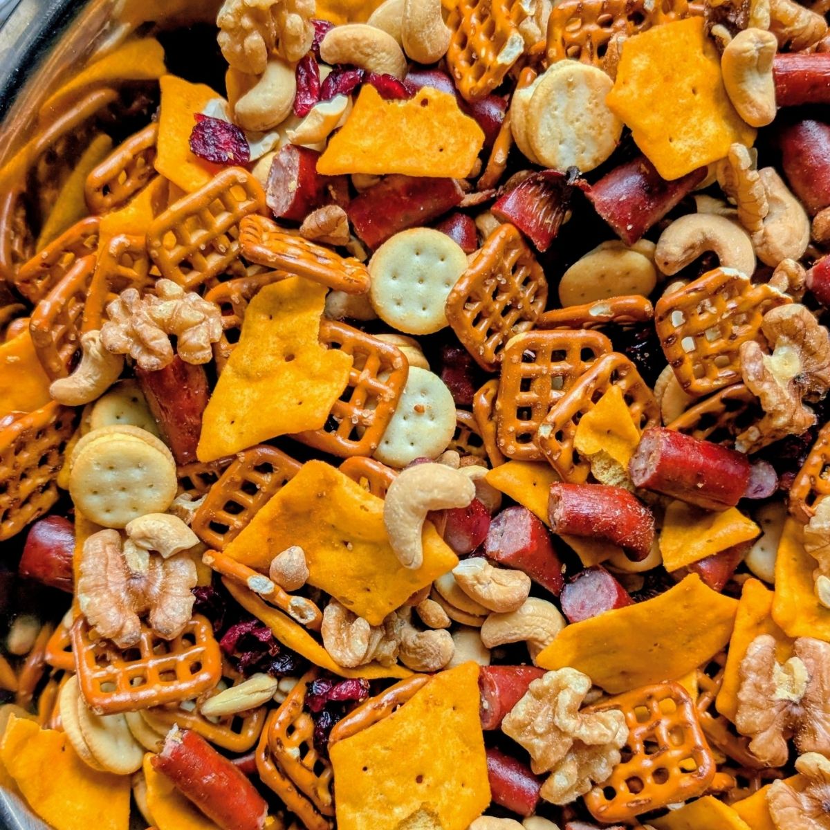 charcuterie snack mix with cheese crackers, pretzels, nuts, pepperoni, and dried fruit