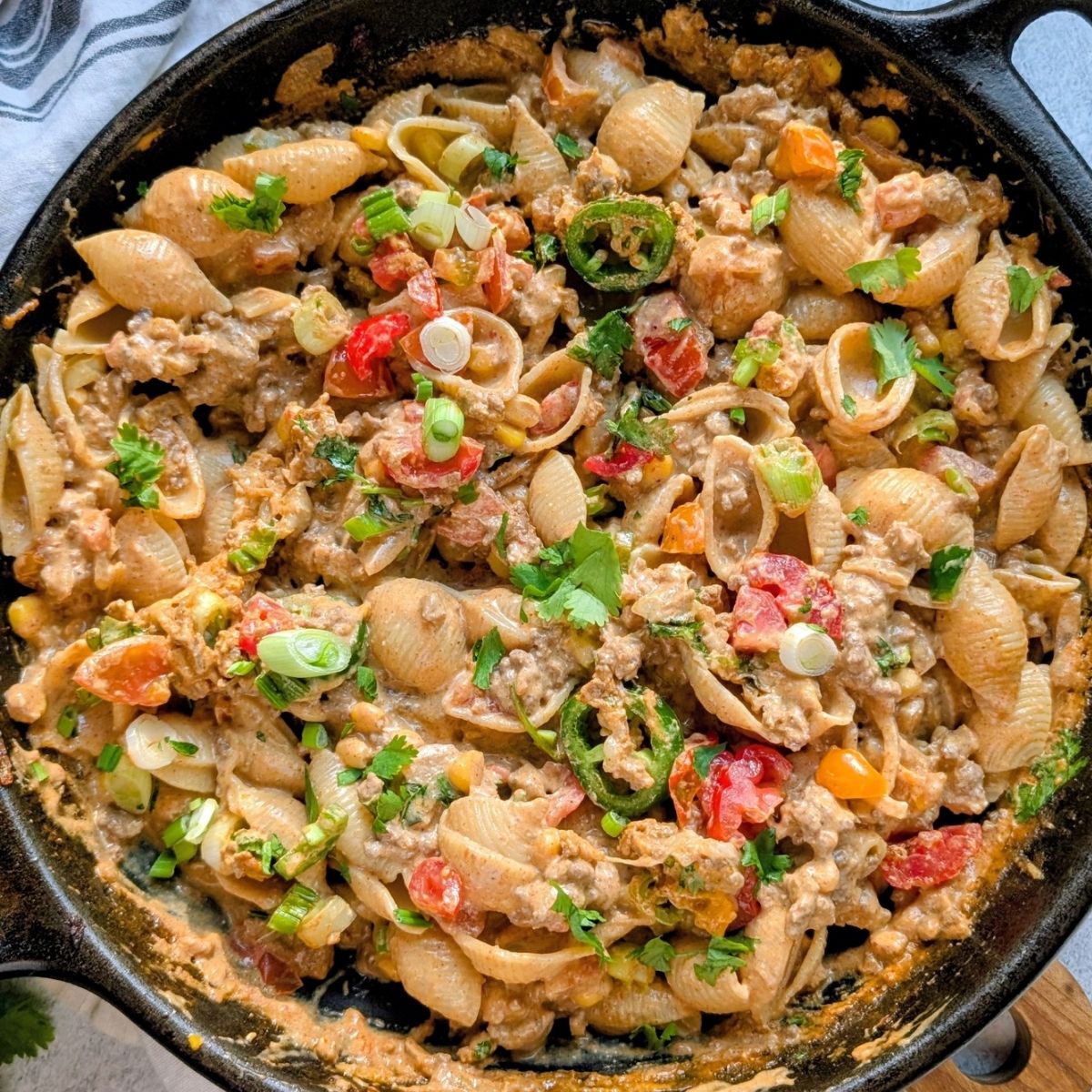 creamy skillet taco pasta with ground beef, taco seasoning, and fresh chopped vegetables